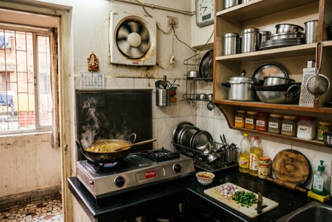Indian kitchen in the afternoon, cooking in progress, exhaust fan above the stove